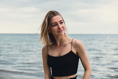 Portrait of young woman standing at beach