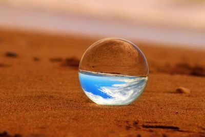 Close-up of crystal ball on sand