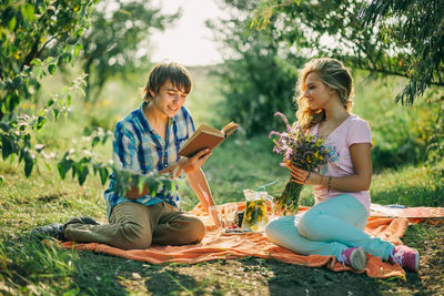 Man reading book by woman on field