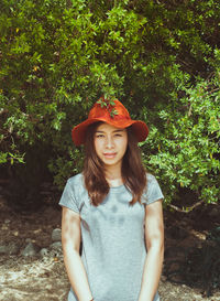 Portrait of beautiful young woman standing against plants