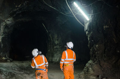 Rear view of people working in cave