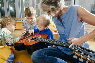 Pre-school teacher showing a guitar to children in kindergarten