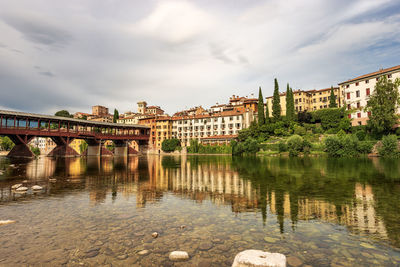 Arch bridge over river against buildings in city