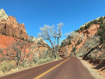 Landscape of road through orange hills and cliffs and bare trees