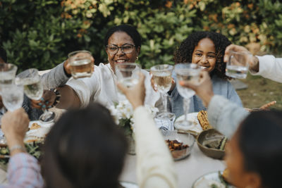 Happy male and female family members toasting drinks at garden party