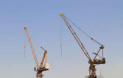 Low angle view of cranes against clear sky