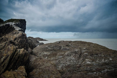 Rock formations on shore against sky