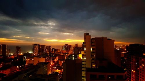 Illuminated cityscape against sky during sunset