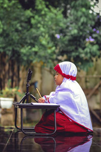 Side view of boy sitting on swing