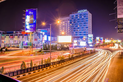 Light trails on city street by buildings at night