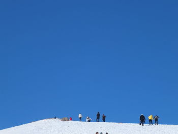 People walking against clear blue sky