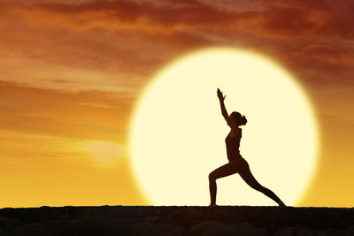 Woman exercising against orange sky