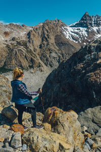 Man sitting on rock against mountain