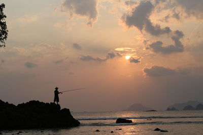 Silhouette of fisherman as the sun sets over the sea, sea coral