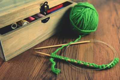 Close-up of woolen ball with knitting needles on table