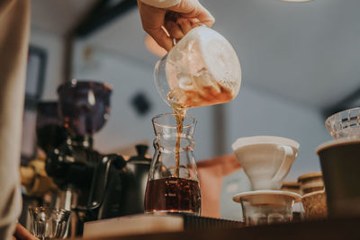 Close-up of hand pouring coffee in cup