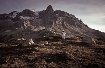 Man standing on rock against sky