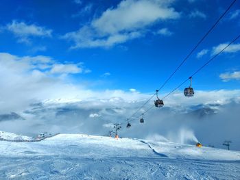 Ski lift over snowcapped mountains against sky