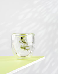 Female hand pours liquid chlorophyll into a glass. glass of liquid chlorophyl on the green table