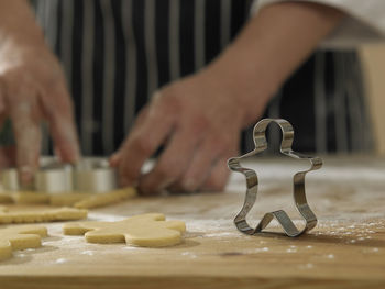 Midsection of chef cutting dough with pastry cutter at table