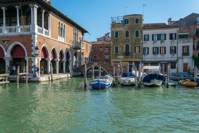 Boats moored in canal against buildings in city