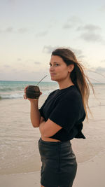 Side view of young woman standing at beach