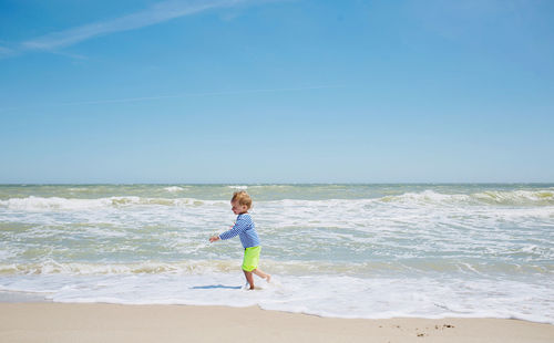 Boy on beach against sky