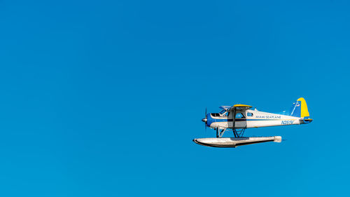 Low angle view of airplane against clear blue sky