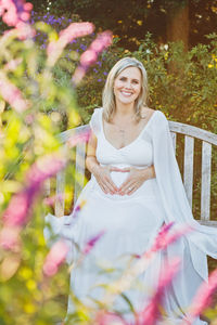 Portrait of smiling woman standing against tree