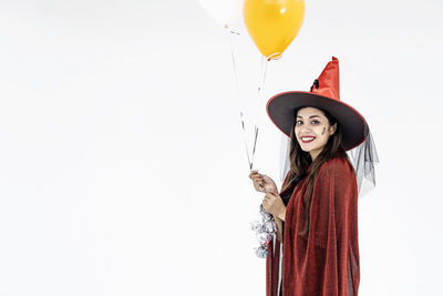 Smiling young woman standing against balloons