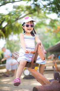 Smiling girl sitting on seesaw in playground