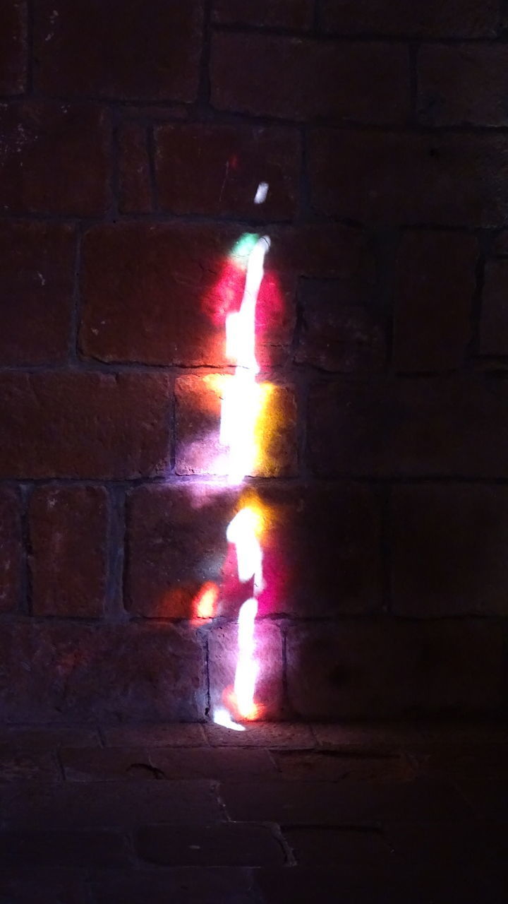 CLOSE-UP OF LIT CANDLES ON WALL