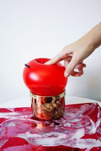 Close-up of hand holding red wineglass against white background