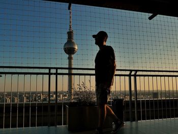 Rear view of man walking by railing against sky