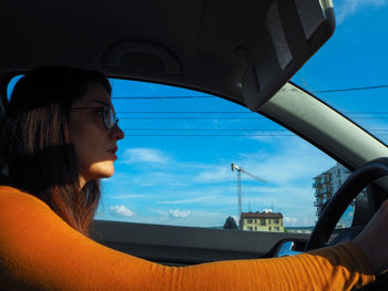 Portrait of young woman looking through car window