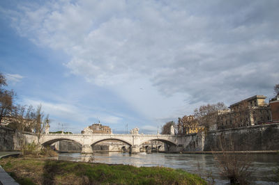 Arch bridge over river against buildings