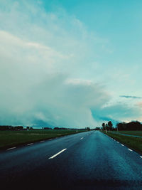 Road amidst field against sky
