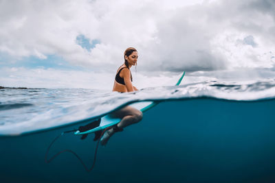 Young woman swimming in sea against sky