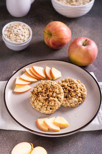 Appetizing crumble of apples and oatmeal on a plate and fruits on the table. vertical view