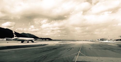View of airport runway against cloudy sky