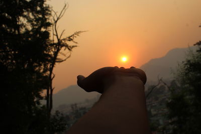 Midsection of person against sky during sunset