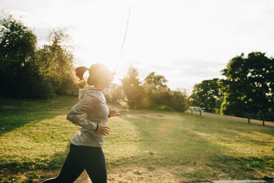 Side view of female athlete jogging at park during sunny day