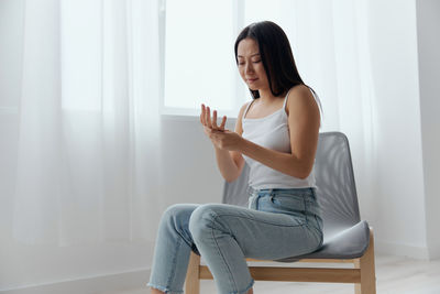 Young woman using mobile phone while sitting on sofa at home