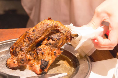 Close-up of womans hand holding roast chicken