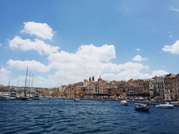 Boats in sea by city against sky