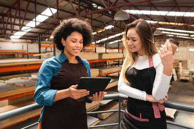 Portrait of smiling young woman using digital tablet while standing at airport