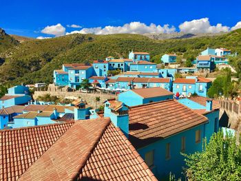 High angle view of houses in town against blue sky