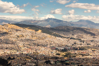 Aerial view of townscape and mountains against sky