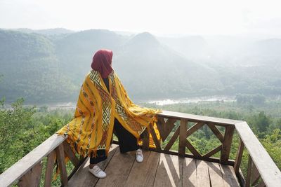 Rear view of woman sitting on mountain