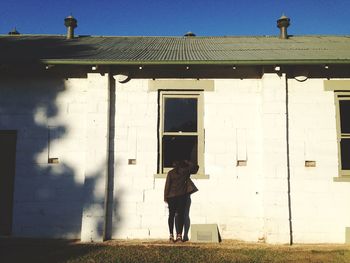 Full length of young woman standing against built structure